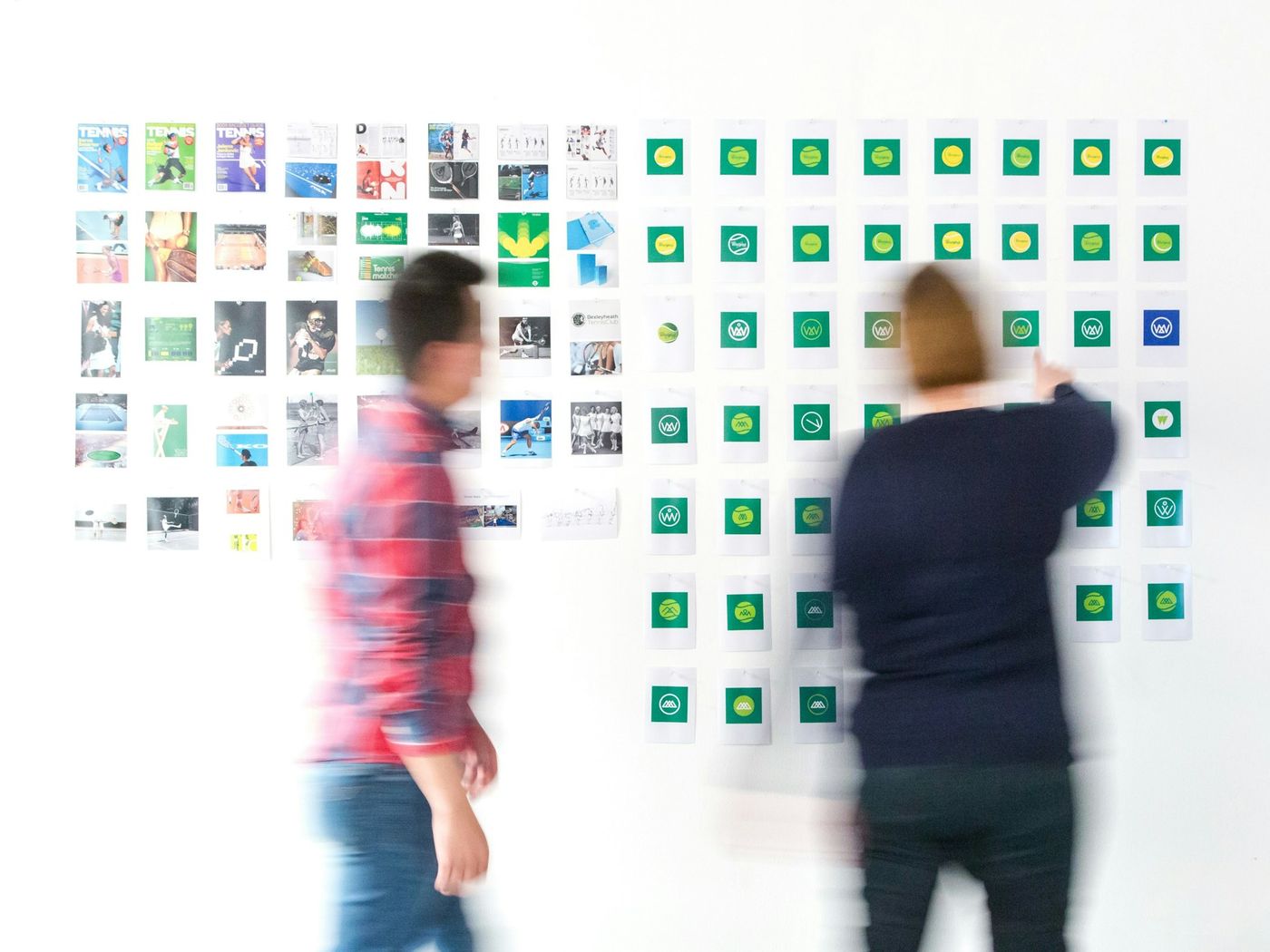 Zwei Personen planen an einer Wand voller Anzeigenentwürfe